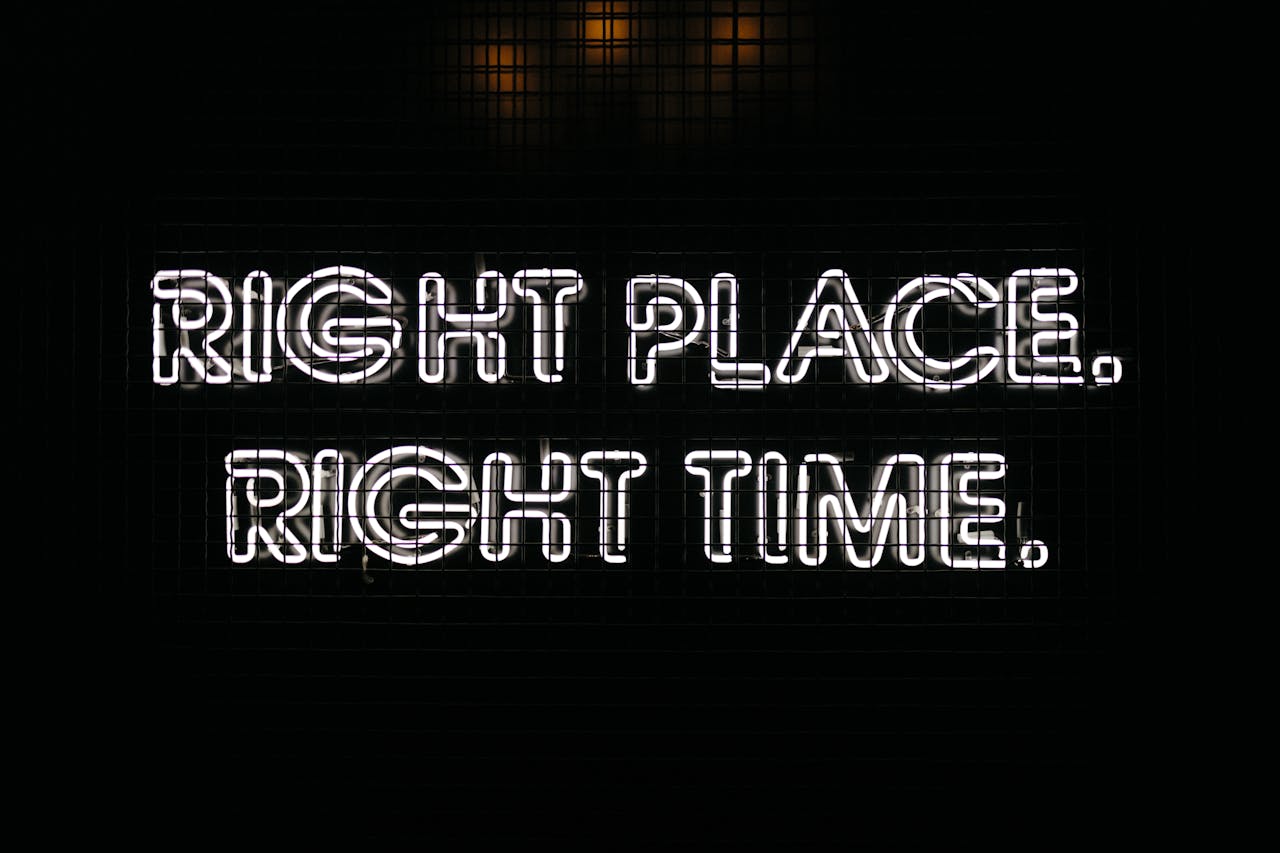 Bright neon sign displaying the text 'Right Place Right Time' against a dark background.